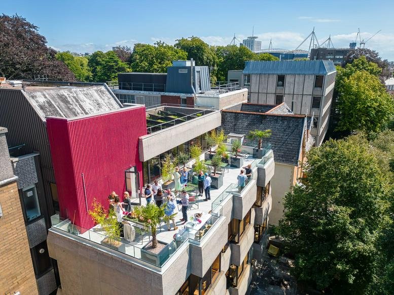 Aerial view of the landscaped rooftop terrace and red facade at 12 Cathedral Road, Cardiff.