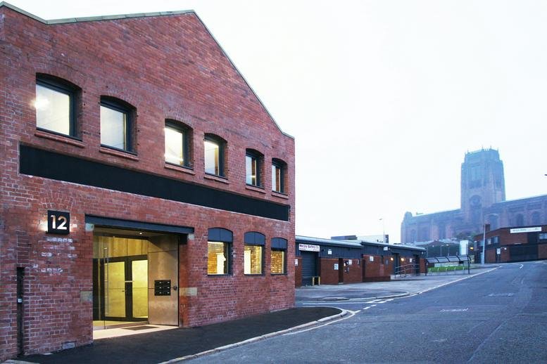 Exterior view of the red brick 12 Jordan Street Studios building against a clear sky.