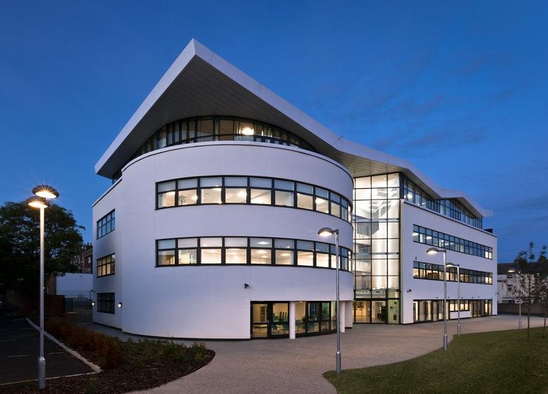 Modern exterior of 12 Lower Clark Street featuring a white curved facade and large windows at dusk.
