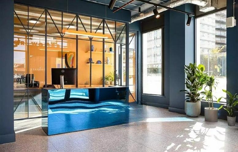 Modern blue mirrored reception desk at 12 Marshgate Lane with warm wood accents and large windows.