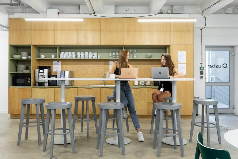 Spacious communal kitchen and coworking area with high stools and wooden cabinetry at 12 Przemysłowa Street, Krakow.