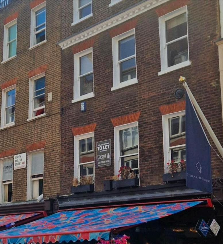 Red brick exterior view of 12, South Molton Street, London featuring traditional sash windows.