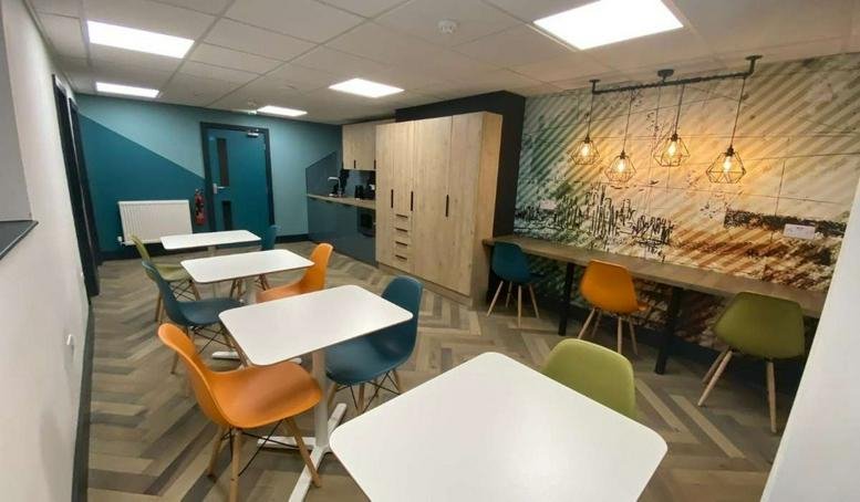 Spacious communal breakout area at 12 Station Parade, Harrogate, featuring cafe tables and vibrant feature walls.