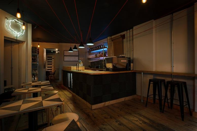 Stylish cafe and bar area at 121 Kings Cross Road, London with geometric tables and ambient lighting.