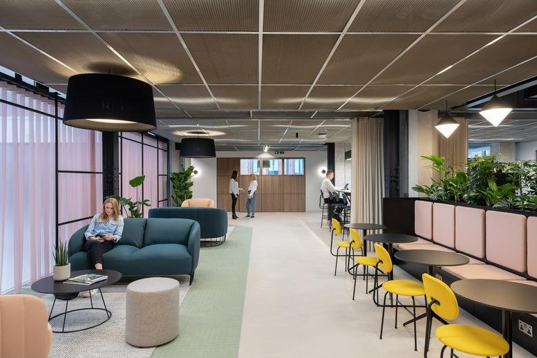 Common area with teal sofas, yellow chairs, and modern lighting at 123 Victoria Street, London.