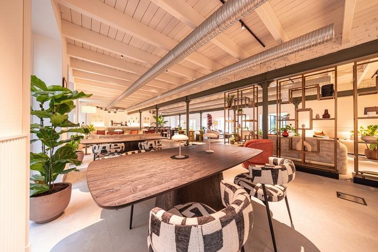 Common area at 125-127 Keizersgracht with wooden tables, patterned armchairs, and lush green plants.