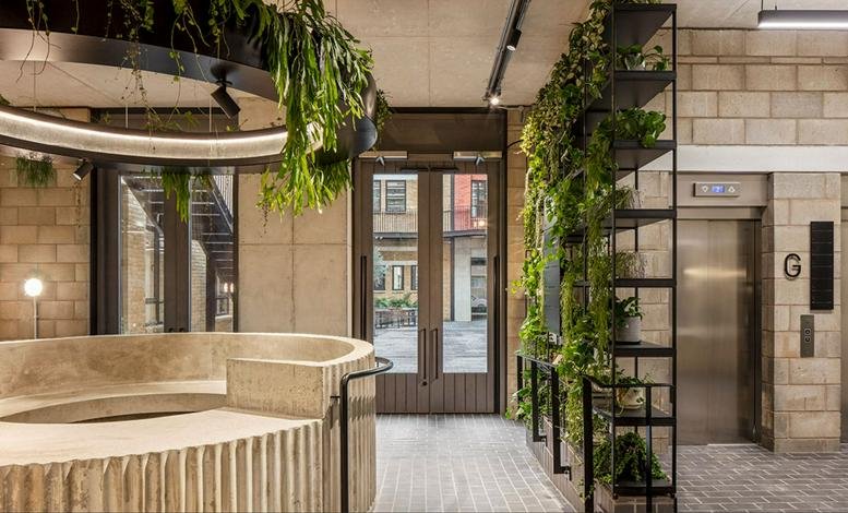 Modern reception lobby at 127 Great Suffolk Street featuring a curved stone desk and lush green plant walls.
