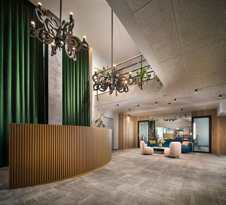 Spacious lobby with a fluted wooden desk, green curtains, and ornate black chandeliers.