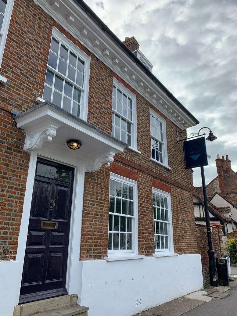 Exterior of the brick building at 13, Upper High Street, Thame with a classic black door and white sash windows.