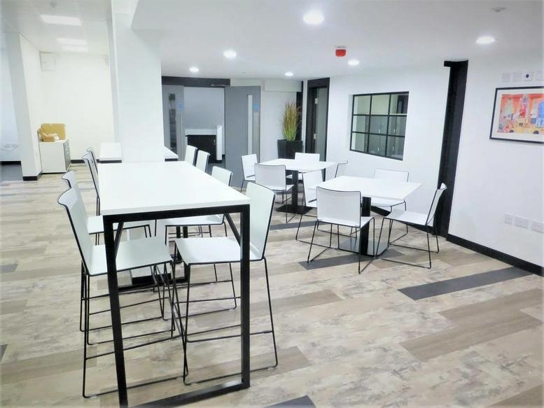 Bright communal break area at 14, Havelock Place, Harrow with white high-top tables and stools.