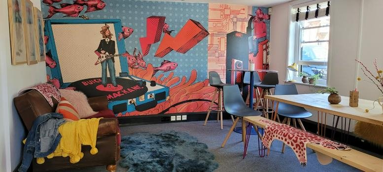 Lounge area showing a leather sofa and a vibrant pop-art wall mural with a window view.
