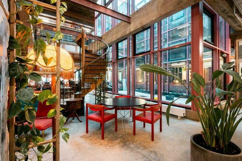 Spacious communal lounge at 140 High Street, Sutton (London) with a spiral staircase and lush indoor plants.