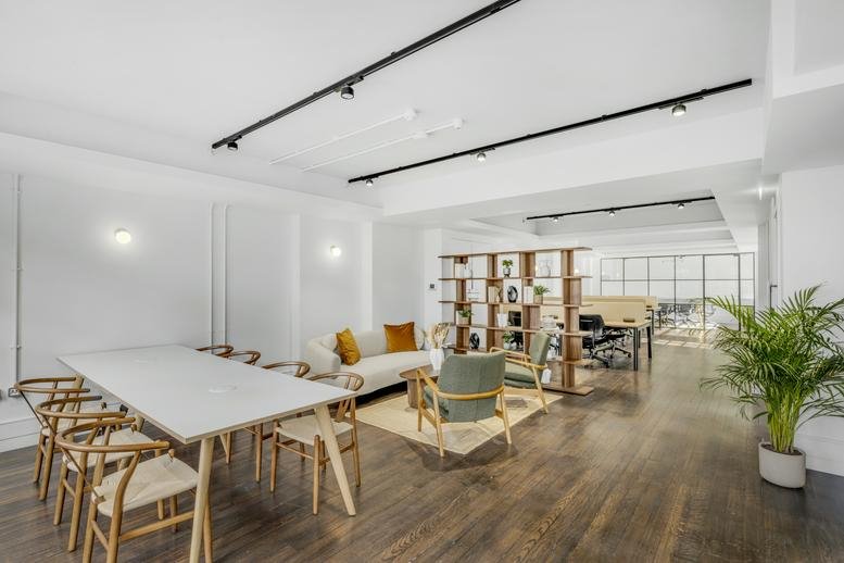 Spacious communal lounge and coworking area with wooden floors and track lighting.