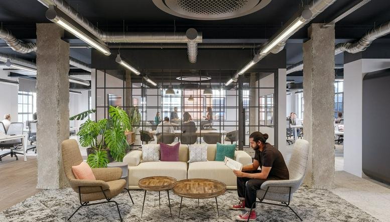 Spacious lounge at Gilray House featuring a cream sofa, patterned rug, and large potted plants.