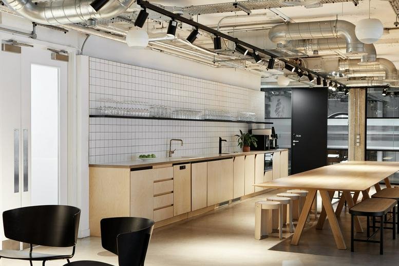 Industrial-style kitchen area with light wood cabinetry and a long wooden table.