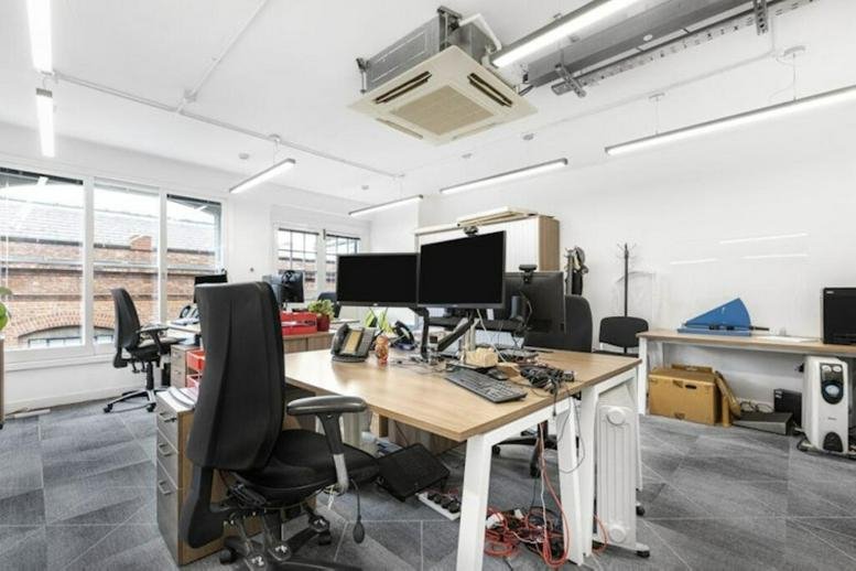 Open-plan office with timber desks and ergonomic chairs.