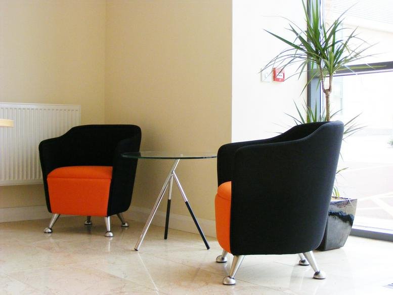 Bright reception area at 15 Olympic Court with orange and black tub chairs and a glass coffee table.