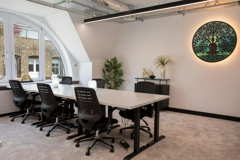 Bright meeting room at 16 Saint John’s Lane with a long white table and tree-of-life wall art.