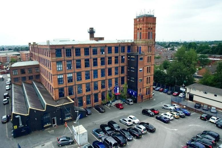 Exterior view of the historic red brick factory building at 160 Oldham Road.