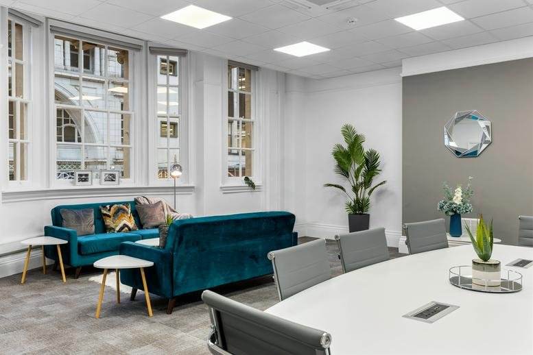 Spacious communal lounge at 18-19 Bennetts Hill featuring teal velvet sofas, plants, and large windows.