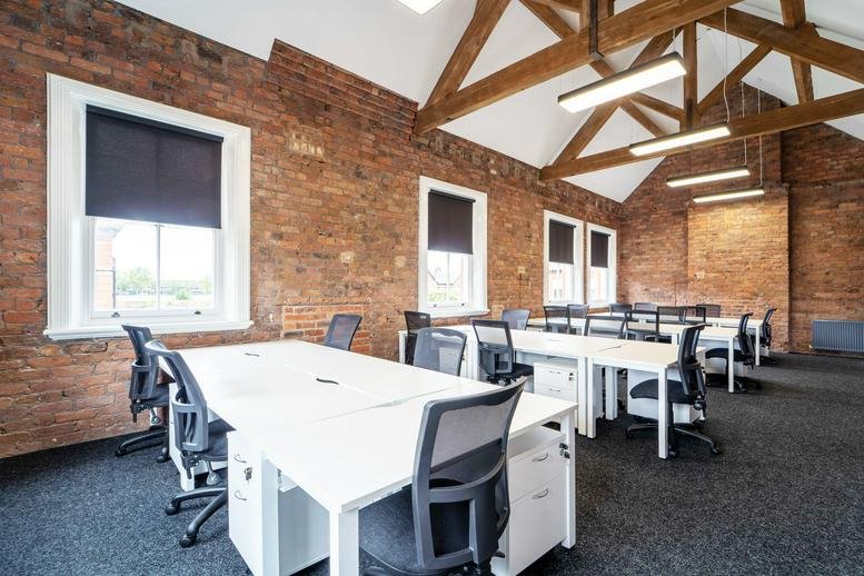 Spacious open-plan office at 18 Clock Tower Park featuring vaulted timber beams and exposed brick walls.