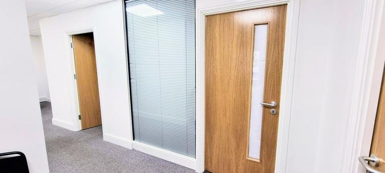Clean white hallway featuring light wood doors and a frosted glass partition.