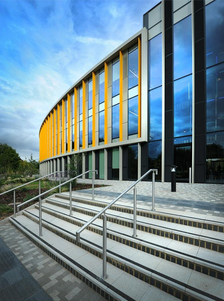 Modern curved building facade with striking yellow vertical fins and large glass panels.