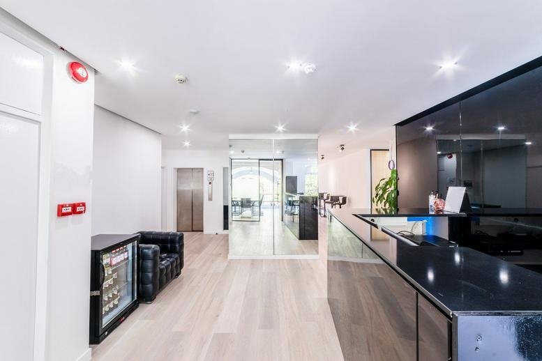 Spacious reception area at 189 Brompton Road featuring a sleek black desk and polished wood floors.