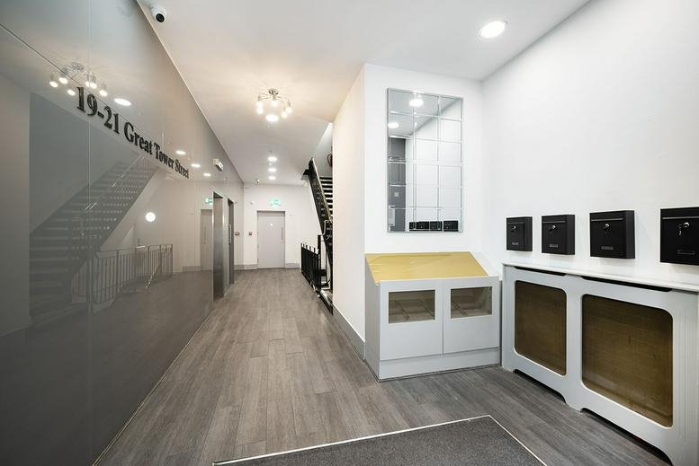 Modern lobby at 19-21 Great Tower Street with grey marble walls and wooden floors.