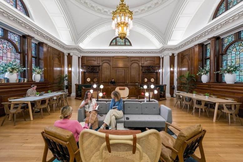 Grand communal lounge with high vaulted ceilings, wood paneling, and a large gold chandelier.