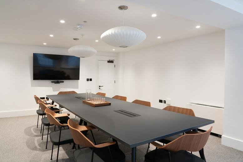 Modern boardroom featuring a long black table and designer pendant lighting.