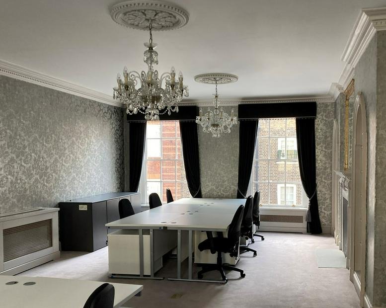 Elegant office suite with patterned wallpaper, chandeliers, and black velvet curtains.