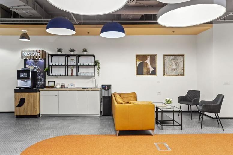 Communal break area at 2 Gara Herastrau Street featuring a coffee station and a modern yellow sofa.