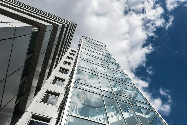 Upward view of the modern glass and steel facade of 2 Queens Walk.