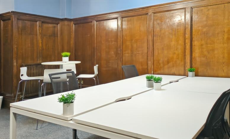 Coworking space featuring wood-paneled walls and a long white desk.