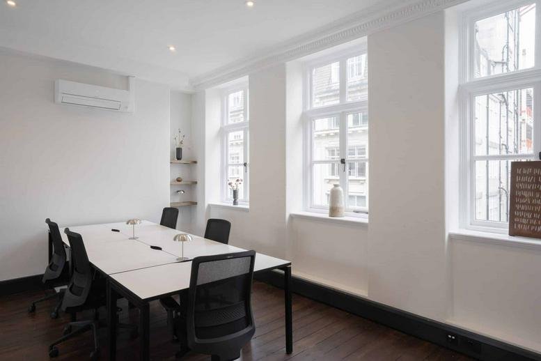 Spacious office space at 20 Eastcastle Street featuring white desks and large sash windows.