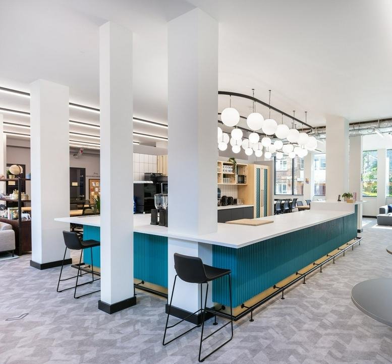Modern communal cafe and breakout area at 20 Red Lion St with a teal bar and spherical pendant lighting.