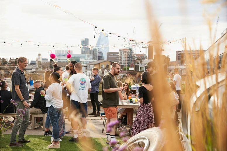 Lively rooftop terrace at 20 St Thomas Street with people socializing against the city skyline.