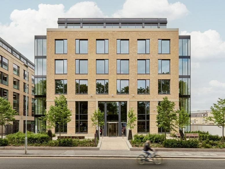 Symmetrical brick exterior of the 20 Station Road, Cambridge building with glass side panels and manicured landscaping.