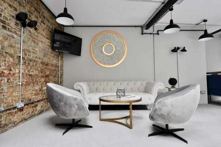 Spacious reception lounge with velvet chairs and a brick feature wall at 200 Borough High Street.