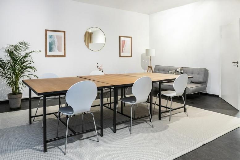 Spacious meeting area at 208, Torstraße, Berlin with wooden tables and circular mirror.