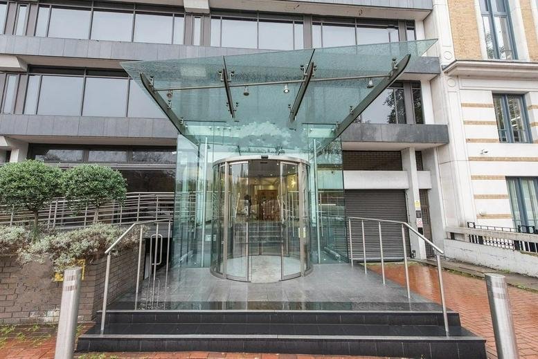 Exterior entrance of 21 Knightsbridge, Belgravia featuring a modern glass canopy and revolving door.