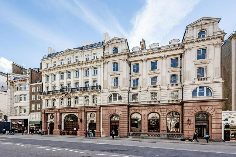 Historic stone facade and entrance of 217, 218 Strand, London under a bright blue sky.