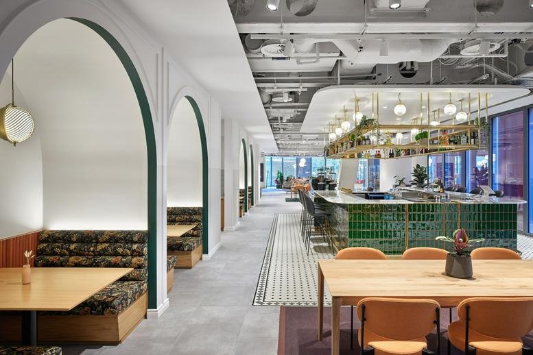 Spacious communal lounge at 22 Bishopsgate, London, Financial District with arched booths and a green tiled bar.