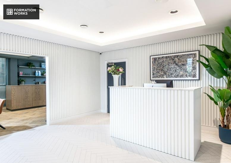 Modern reception desk with vertical wood panelling and a large potted plant.
