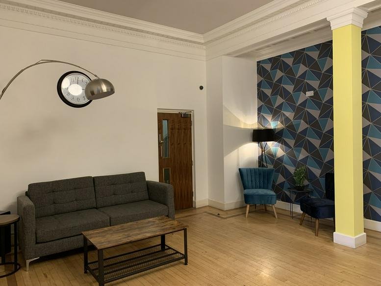 Spacious reception lounge at 22 Lansdown Industrial Estate with a grey sofa and patterned feature wall.