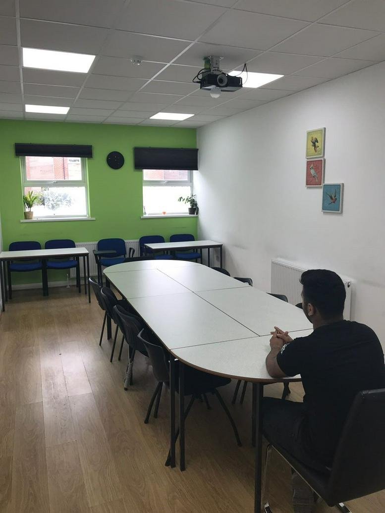 Meeting room at 221-227 High Road, Harrow featuring a long white table and bright green accent wall.