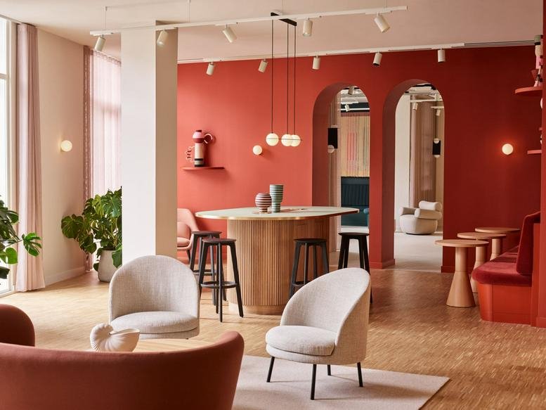 Modern lounge area with vibrant red walls, arched doorways, and light-colored armchairs.