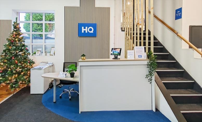 Bright reception desk with HQ branding and a decorated Christmas tree.