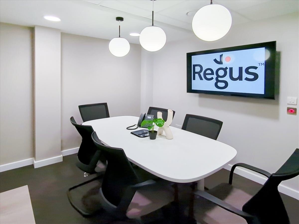 A professional meeting room at 23-25 Market Street featuring a white oval table and wall-mounted screen.